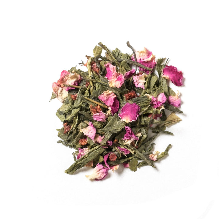 Flat lay photo of green tea with raspberry pieces and red rose petals.